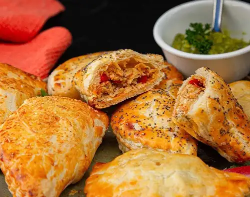 Empanadas de hojaldre rellenas de pollo acompañadas con salsa en Doña Dicha.