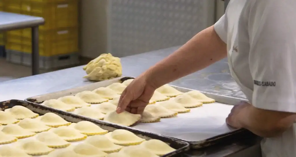 Preparación artesanal de empanadas en la cocina de panadería Doña Dicha sede Ciudad Jardín Norte.
