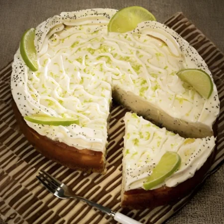 Cheesecake artesanal de limón y semillas de amapola decorado con crema y rodajas frescas.