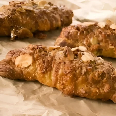 Croissants artesanales horneados cubiertos con almendras fileteadas tostadas.