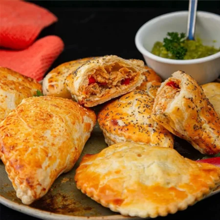Empanadas de hojaldre horneadas con semillas de amapola rellenas de pollo desmechado y pimentón.