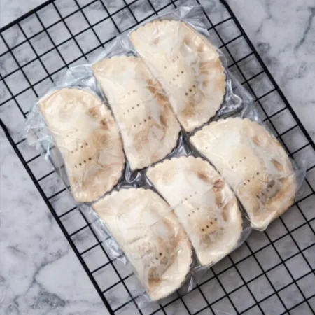 Paquete al vacío con empanadas de carne congeladas de masa hojaldrada listos para horneado.