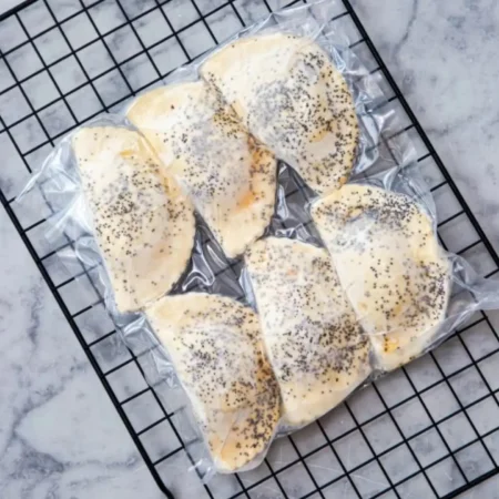 Paquete al vacío con empanadas de pollo congeladas decoradas con semillas de amapola.