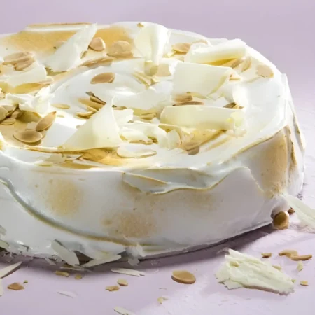 Torta postre de tres leches artesanal cubierta con hojuelas de chocolate blanco y almendras.