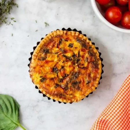 Quiche individual caprese de tomate, albahaca fresca y queso mozzarella en molde tartero.