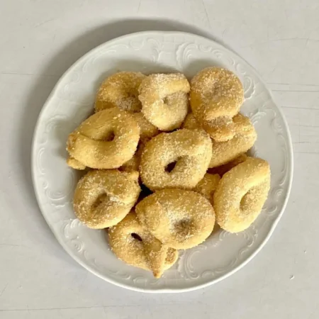Plato blanco con rosquitas artesanales de mantequilla espolvoreadas con fina azúcar blanca.