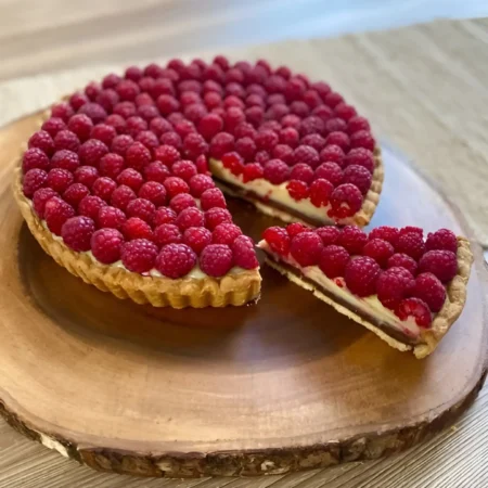 Tartaleta artesanal mestiza con base crujiente, con abundante cobertura de frambuesas frescas.