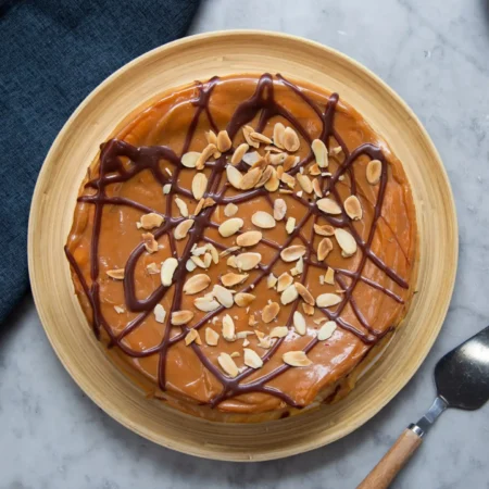 Torta Broselina artesanal cubierta de arequipe, hilos de chocolate y almendras fileteadas tostadas.