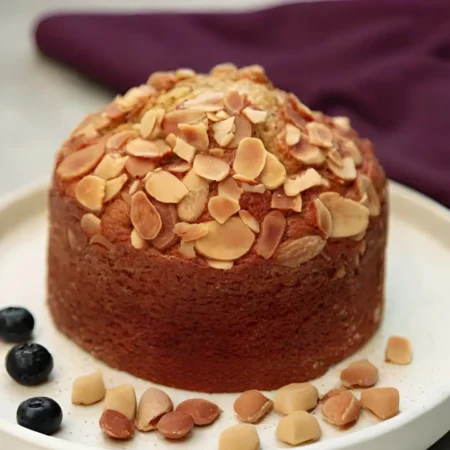 Torta artesanal saludable de arándanos y almendras sin azúcar añadida en plato con frutos secos.