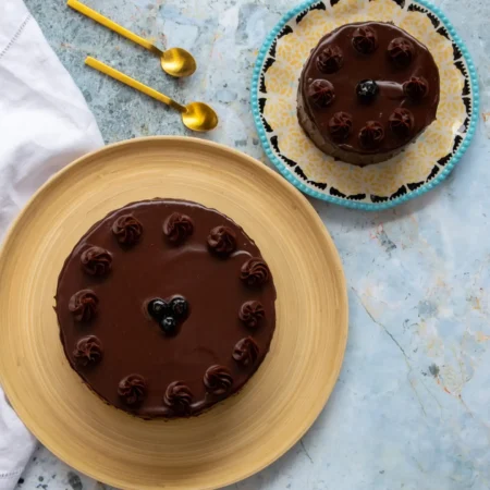 Torta artesanal de chocolate húmeda cubierta con ganache brillante y rosetas de chocolate.